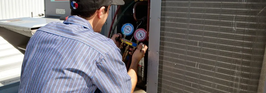 HVAC technician servicing a condenser unit in Duxbury